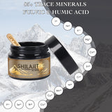 A jar of SHILAJIT resin in front of a mountainous backdrop with a hiker in the distance. The label on the jar indicates the product is a 'Purifying Himalayan resin gift' and provides additional details about the product.