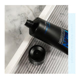 Black facial cleanser tube with blue text on a marble surface