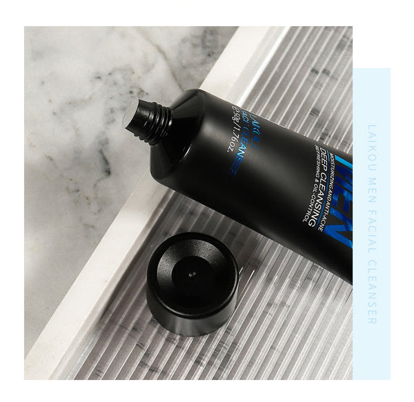 Black facial cleanser tube with blue text on a marble surface