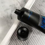 Black skincare bottle with blue text on a marble surface